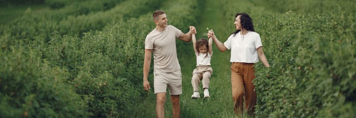 A happy family walking in a lush, green rural field together.